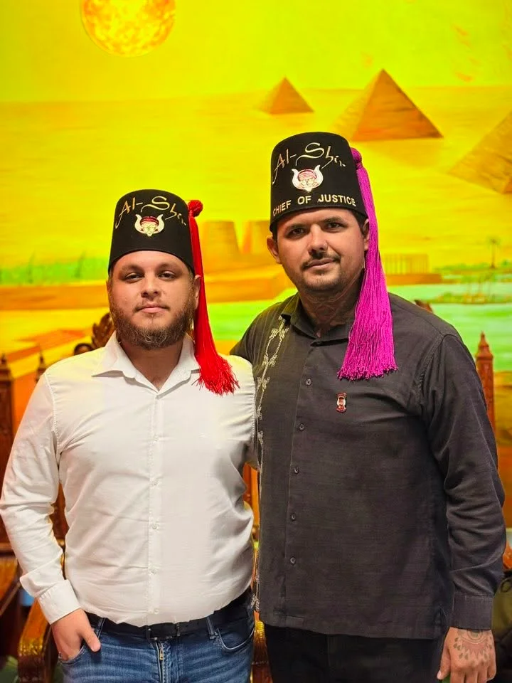 Dos participantes con fez en un encuentro fraternal.