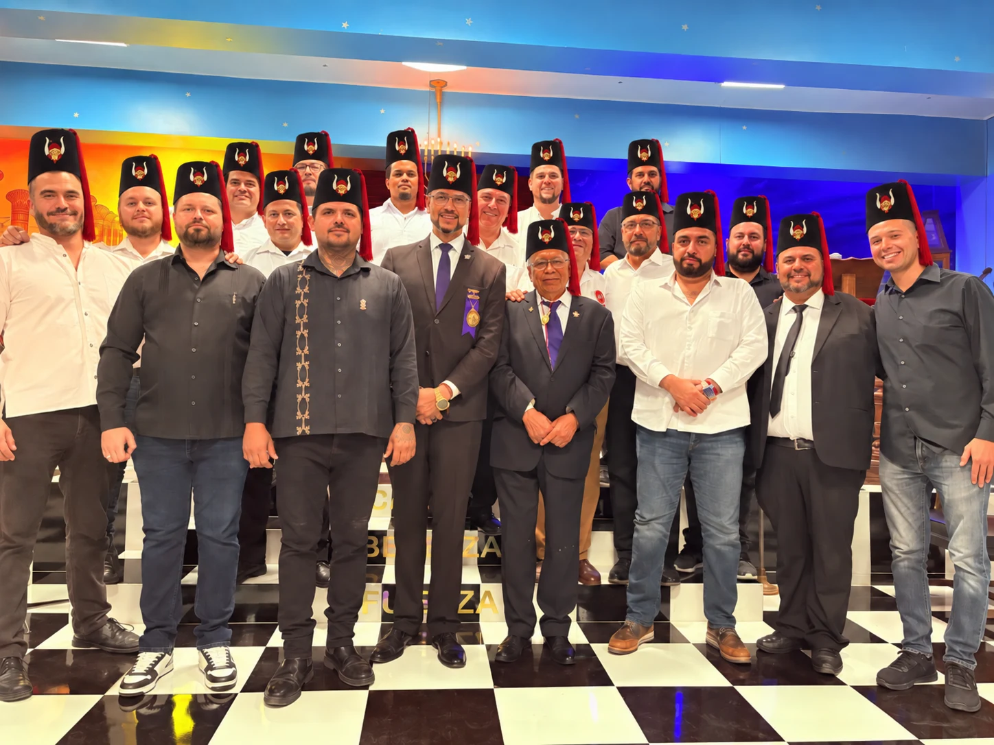Retrato de grupo con fezzes negros y borlas rojas en un encuentro fraternal.